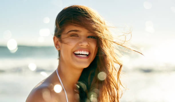 Jeune femme souriante au teint hâlé et lumineux profitant d'un bronzage artificiel uniforme, en lien avec les étapes pour obtenir un bronzage à la maison conseillé par la clinique laser Paris 8 Élysées Derm